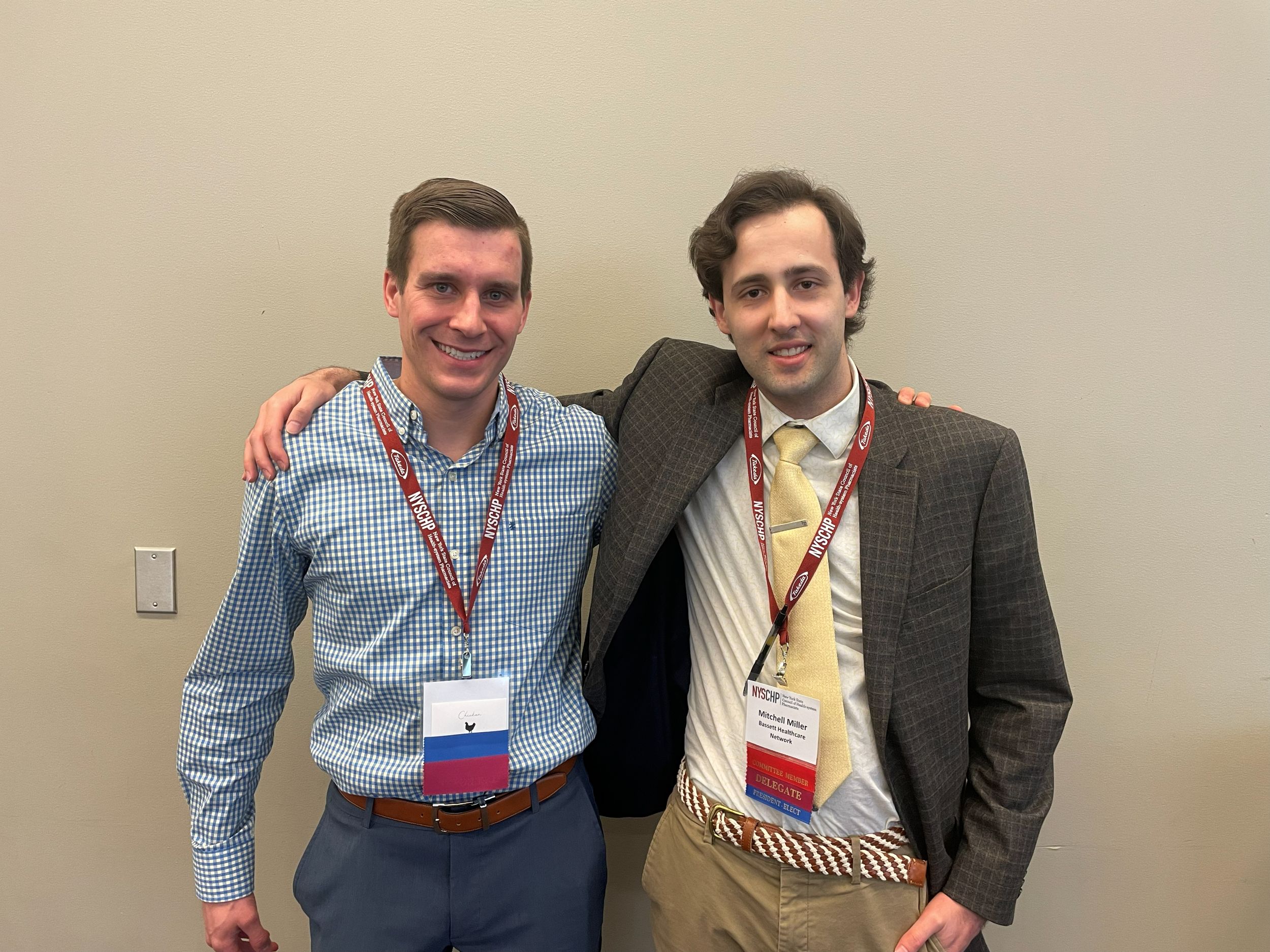 Two young men pose for the camera with one's arm over the other's shoulders